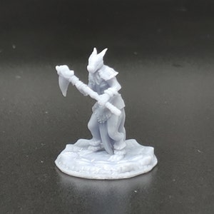 May include: A grey 3D printed miniature of a humanoid figure with a reptilian head and a tail. The figure is holding a hand axe and is standing on a round base.