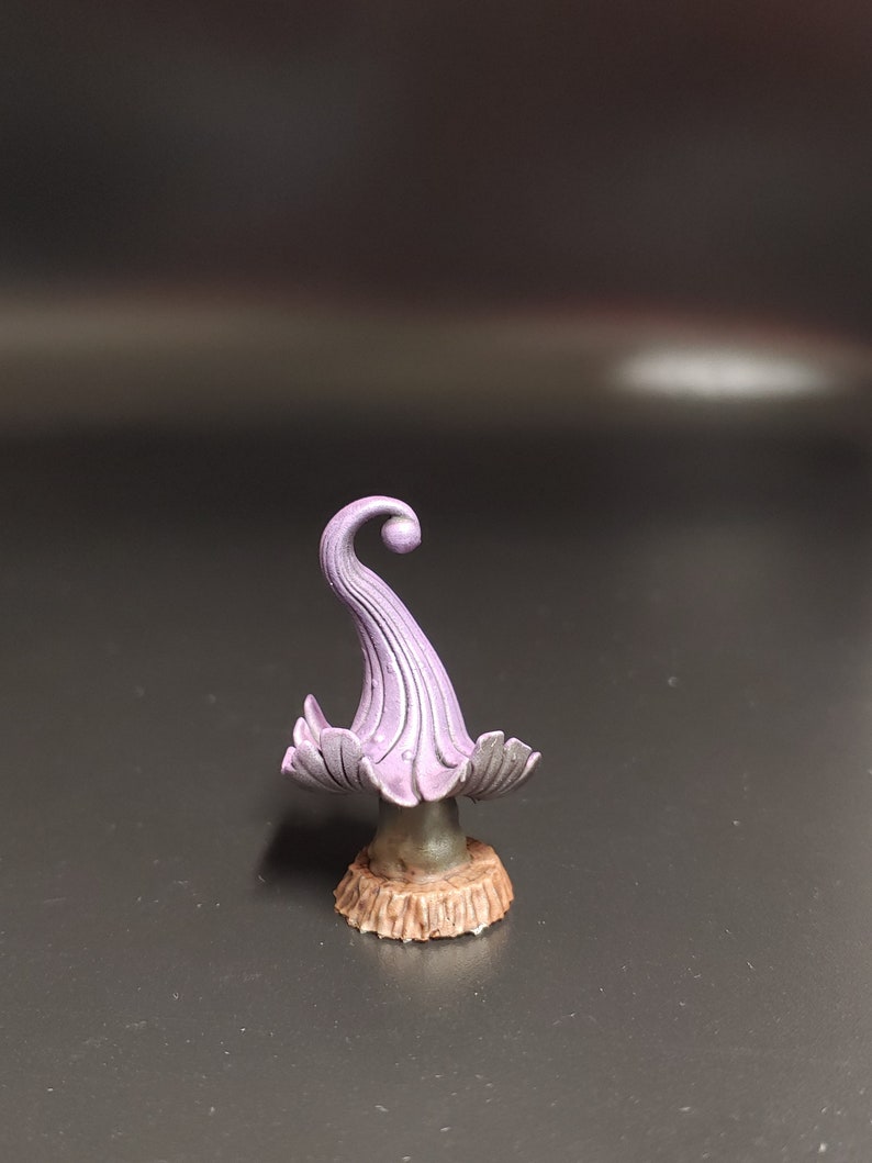May include: A small, purple, mushroom-shaped figurine with a curled top and a brown base.