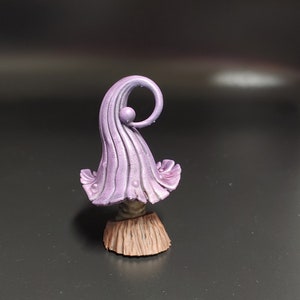 May include: A purple and brown miniature mushroom figurine with a curled top and a textured base.