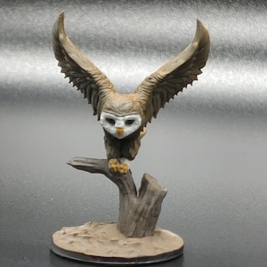 May include: A brown and white owl figurine with outstretched wings perched on a tree stump. The owl has a white face with black eyes and a yellow beak. The figurine is on a brown base.