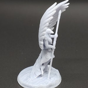 May include: A pale blue figurine of a winged humanoid figure holding a staff. The figure has large, detailed wings and is standing on a circular base. The figurine is likely a fantasy or mythological character.