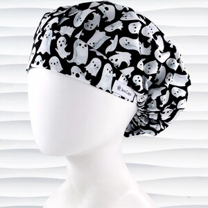 Bouffant style surgical scrub cap with white animated ghosts all over this black cotton fabric.