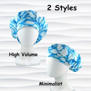 May include: Two styles of scrub caps are displayed on mannequin heads. The caps feature a blue and white cloud-like pattern. One cap is high volume, and the other is minimalist. The text "2 Styles", "High Volume", and "Minimalist" are also visible.