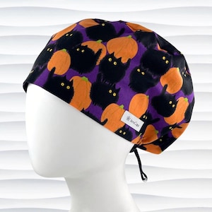 May include: A purple surgical scrub cap with a repeating pattern of black cats and orange pumpkins. The cap has a white tag with the text "JensCaps". The cap is designed to be worn in a medical setting.