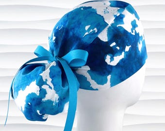 May include: A blue and white patterned scrub cap with a matching blue ribbon. The cap features a watercolor-like design with shades of blue and white. The cap is tied in a bow at the back.