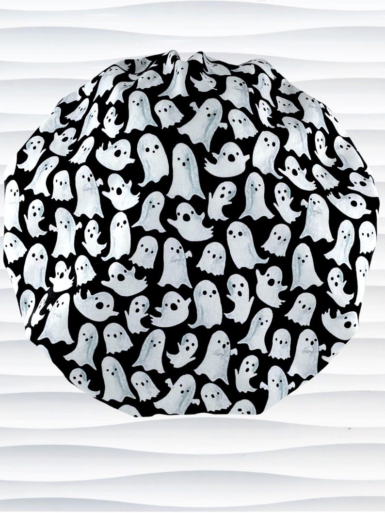 Bouffant style surgical scrub cap with white animated ghosts all over this black cotton fabric.