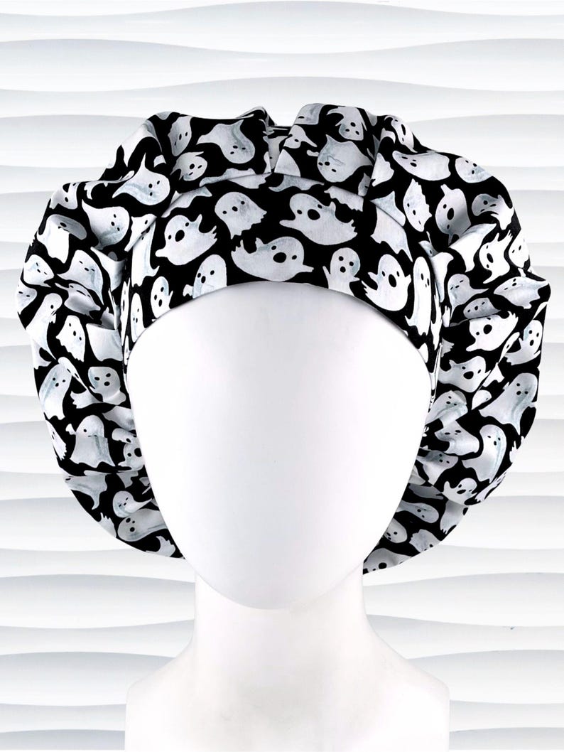 Bouffant style surgical scrub cap with white animated ghosts all over this black cotton fabric.