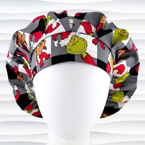 May include: A patterned scrub cap featuring a repeating design of a green character with a red outfit and a brown dog-like character, set against a black, white, and gray checkered background. The cap is designed to fit over the head.