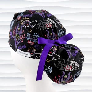 May include: Black scrub cap with a purple bow, featuring a colorful pattern of cartoon villains. The design includes images of Ursula, Maleficent, and other characters. The text "Villains" and "JensCaps" are visible on the cap.