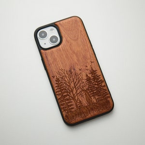May include: A brown wooden phone case with a laser-engraved design of trees and birds. The case has a black rubber bumper.