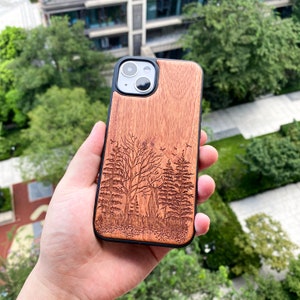 May include: A wooden phone case with a laser-engraved forest scene. The case is brown with a black border and features a design of trees and birds.