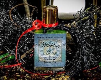 May include: A green glass bottle with a gold cap and a red ribbon tied around it. The bottle is labeled "Witching Hour Magical Ritual Oil" with a clock face design. The bottle is sitting on a bed of brown and gold glitter.