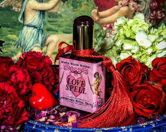 May include: A small bottle of perfumed ritual oil with a red label that says "Love Spell" and "Wynter Willow Witchery". The bottle is surrounded by red roses, carnations, and a red heart.