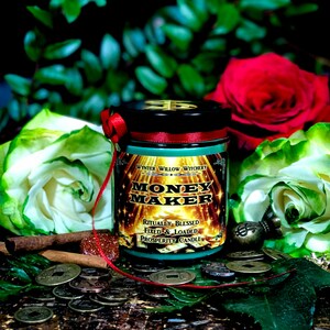 Puede incluir: Un tarro de vela verde y dorado con el texto "Money Maker" y "Ritually Blessed, Fixed & Loaded Prosperity Candle" en la etiqueta. La vela est&aacute; rodeada de monedas y flores.