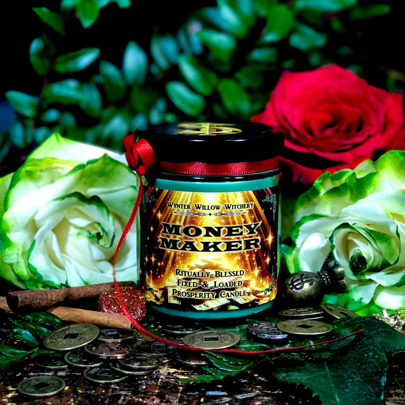 Puede incluir: Un tarro de vela verde y dorado con el texto "Money Maker" y "Ritually Blessed, Fixed & Loaded Prosperity Candle" en la etiqueta. La vela est&aacute; rodeada de monedas y flores.