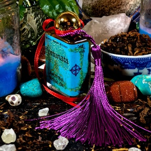 May include: A small bottle of blue and gold oil with a purple tassel. The bottle is labeled "Fortunata Ancestral Ritual Oil" and "Wynter Willow Witchery".