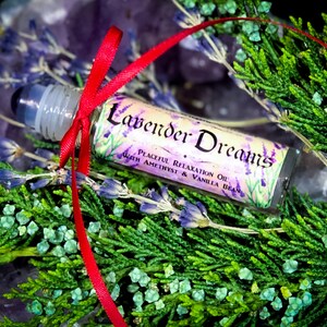 Puede incluir: Un peque&ntilde;o frasco de vidrio con rodillo con una cinta roja atada alrededor. El frasco est&aacute; etiquetado con "Lavender Dreams Peaceful Relaxation Oil with Amethyst & Vanilla Bean".