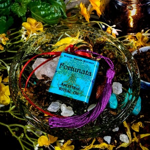 May include: A small blue bottle with a red and purple tassel. The bottle is labeled "Wynter Willow Witchery Fortunata Ancestral Ritual Oil".