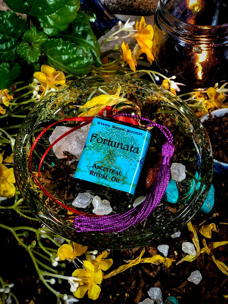 May include: A small blue bottle with a red and purple tassel. The bottle is labeled "Wynter Willow Witchery Fortunata Ancestral Ritual Oil".