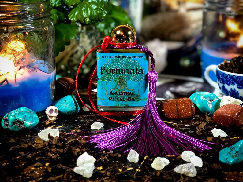 May include: A small bottle of blue and green ritual oil with a purple tassel. The bottle is labeled "Winter Widow Witchery Fortunata Ancestral Ritual Oil".