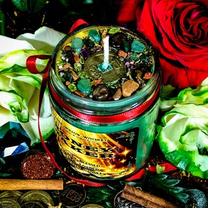 Puede incluir: Vela de vidrio verde en un frasco con una cinta roja y una vela blanca en el interior. El frasco est&aacute; lleno de piedras verdes, marrones y doradas. La etiqueta en el frasco dice "Money Maker" con las palabras "Naturally Blessed, Potently Loaded, Ritual Candle" debajo.