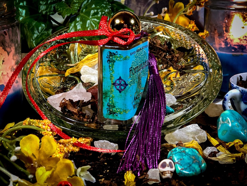 May include: A small blue glass bottle with a gold top and a purple tassel. The bottle is labeled "Fountain of Youth" and "Angelic Ritual Oil". The bottle is surrounded by crystals, dried flowers, and a skull.