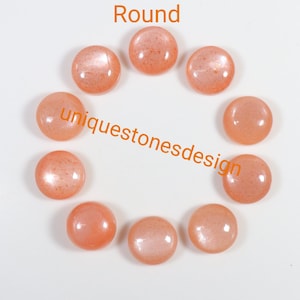 May include: Ten round, peach-coloured sunstone cabochons arranged in a circle on a white background. The text "uniquestonesdesign" is printed in orange below the stones.