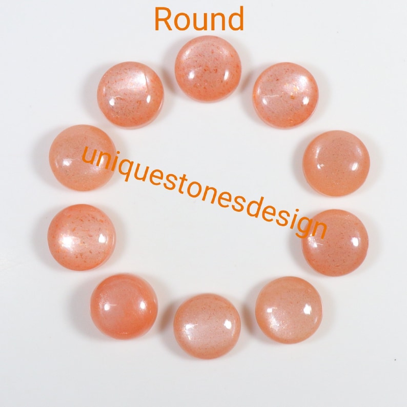 May include: Ten round, peach-coloured sunstone cabochons arranged in a circle on a white background. The text "uniquestonesdesign" is printed in orange below the stones.