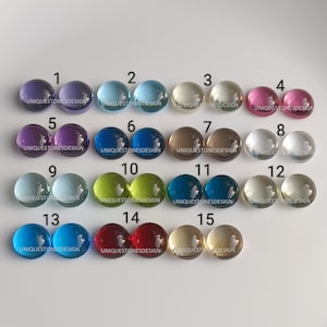 Può includere: Quindici cabochon rotondi in vetro di vari colori, numerati da 1 a 15. Ogni cabochon ha il testo "UNIQUESTONESDESIGN" stampato sul fondo.