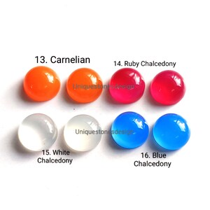 May include: Six round, smooth, polished gemstones in various colors. From left to right: orange carnelian, yellow carnelian, red ruby chalcedony, white chalcedony, blue chalcedony, and light blue chalcedony.