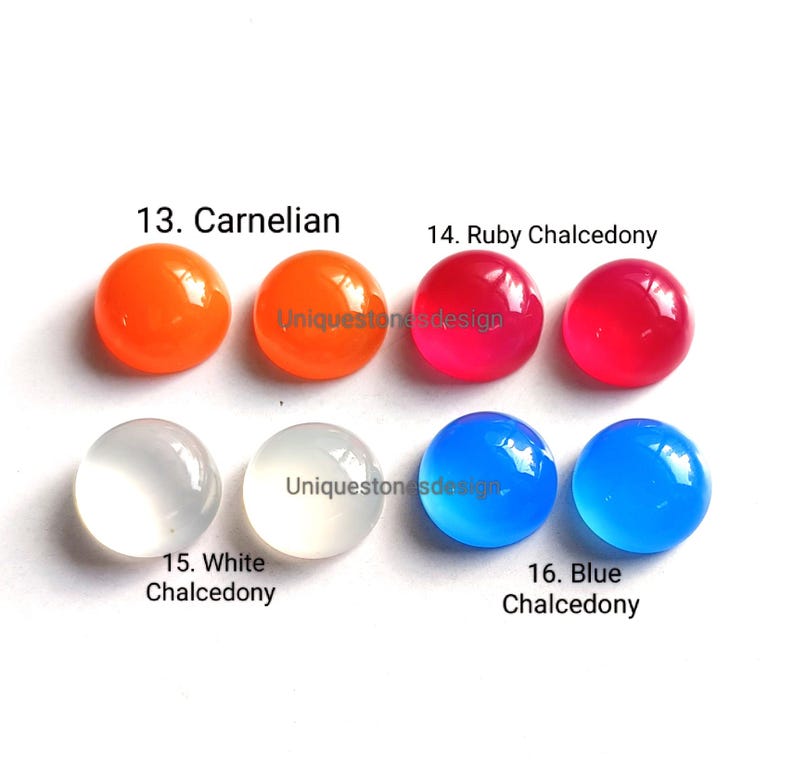May include: Six round, smooth, polished gemstones in various colors. From left to right: orange carnelian, yellow carnelian, red ruby chalcedony, white chalcedony, blue chalcedony, and light blue chalcedony.