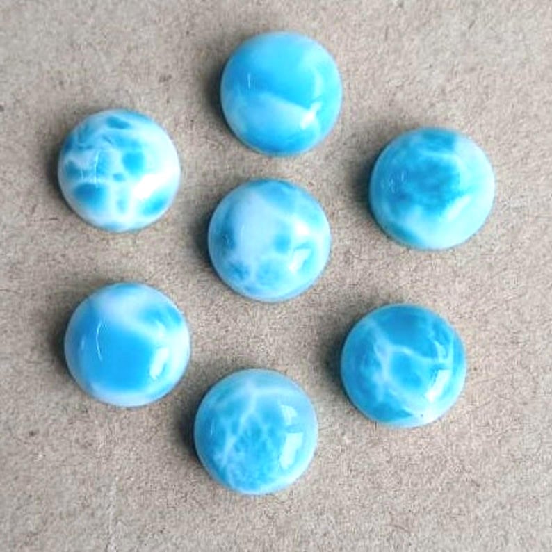 以下が含まれることがあります： 渦巻き模様の入った、丸い青と白のcabochonカットの宝石が7つ。
