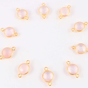 May include: Ten gold-toned connectors with pale pink gemstone accents. Each connector has two loops for attaching jewelry.