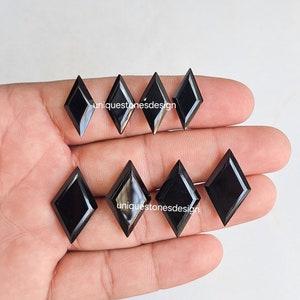 May include: Seven black diamond-shaped gemstones with a polished finish. The gemstones are arranged in two rows on a hand.