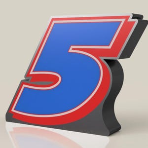 May include: A three-dimensional number five with a blue center, a white outline, and a red border. The number is on a gray background.