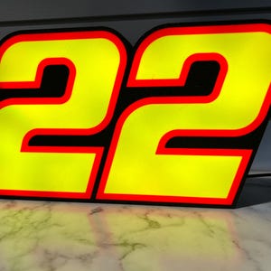 May include: A yellow number 22 with a black outline and a red border. The number is illuminated and appears to be a sign or decoration.