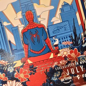 May include: A poster featuring a red and blue Spider-Man figure sitting on a brick wall overlooking a city skyline. The foreground includes stylised flowers and foliage. Text reads EXCLUSIVELY IN MOVIES JULY, prime, and FA.