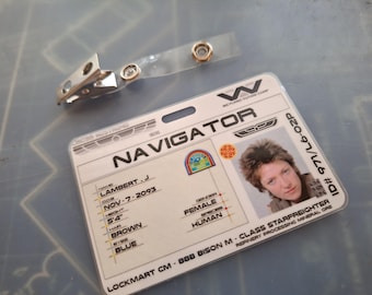 May include: A white plastic ID card with the text "NAVIGATOR" and "WEYLAND-YUTANI CORP" printed on it. The card has a photo of a person with brown hair and a blue shirt. The text "ID# 971/L6-02P" is printed on the right side of the card.