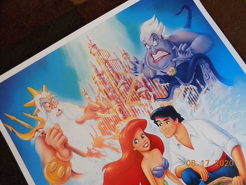 May include: A colorful illustration of characters from the Disney movie The Little Mermaid. Ariel, the mermaid princess, is in the foreground with Prince Eric. King Triton, Ariel's father, is in the background with his trident. Ursula, the sea witch, is in the upper left corner. The background features a golden castle.
