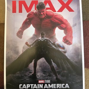 Op de afbeelding: Een filmposter voor Captain America: Brave New World, met een rode Hulk die boven een figuur in een zwart pak en cape staat. De poster is voor de IMAX-release van de film en bevat de tekst "FILMED FOR IMAX" en "FEBRUARY 14".