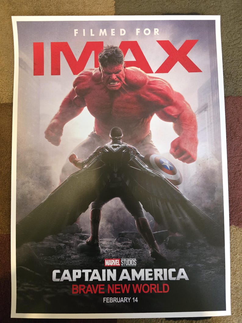 Op de afbeelding: Een filmposter voor Captain America: Brave New World, met een rode Hulk die boven een figuur in een zwart pak en cape staat. De poster is voor de IMAX-release van de film en bevat de tekst "FILMED FOR IMAX" en "FEBRUARY 14".
