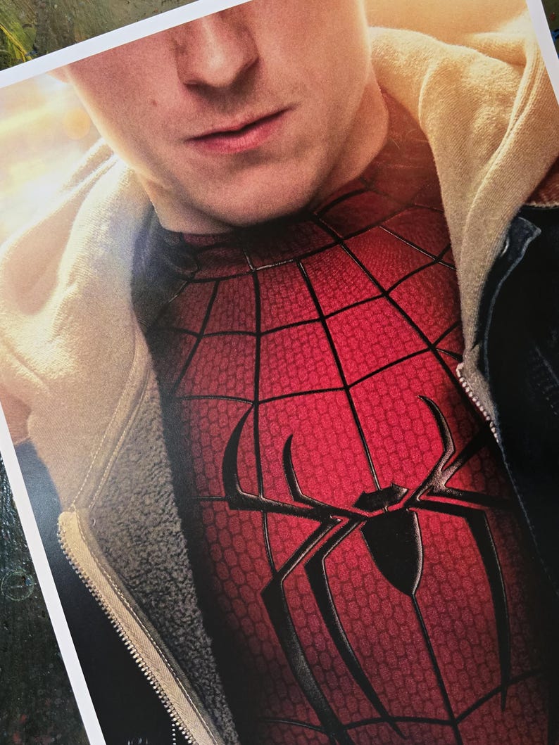 May include: A red and black Spider-Man costume top featuring a textured web pattern and a large black spider emblem on the chest, worn underneath a beige hooded jacket with a dark zipper and a visible fleece-lined interior texture.
