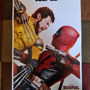 以下が含まれることがあります： 映画「デッドプール＆ウルヴァリン」のポスター。デッドプールは赤と黒、ウルヴァリンは黄色と黒の衣装を着ている。ポスターの上部には「Only in Theaters July 26」の文字、下部にはマーベル・スタジオのロゴが記されている。