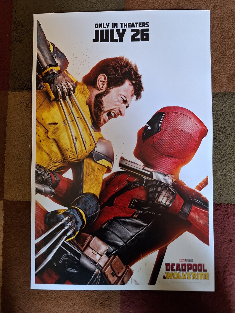 以下が含まれることがあります： 映画「デッドプール＆ウルヴァリン」のポスター。デッドプールは赤と黒、ウルヴァリンは黄色と黒の衣装を着ている。ポスターの上部には「Only in Theaters July 26」の文字、下部にはマーベル・スタジオのロゴが記されている。