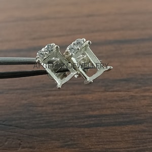 May include: A pair of silver earring settings with a square shape and small clear cubic zirconia stones around the perimeter.