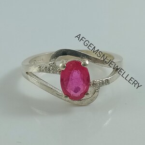 Puede incluir: Un anillo de plata con una piedra ovalada rosa y peque&ntilde;as piedras transparentes en la banda. El anillo est&aacute; engastado en un dise&ntilde;o delicado y retorcido. El texto "AFGEMSNJEWELLERY" es visible en el fondo.