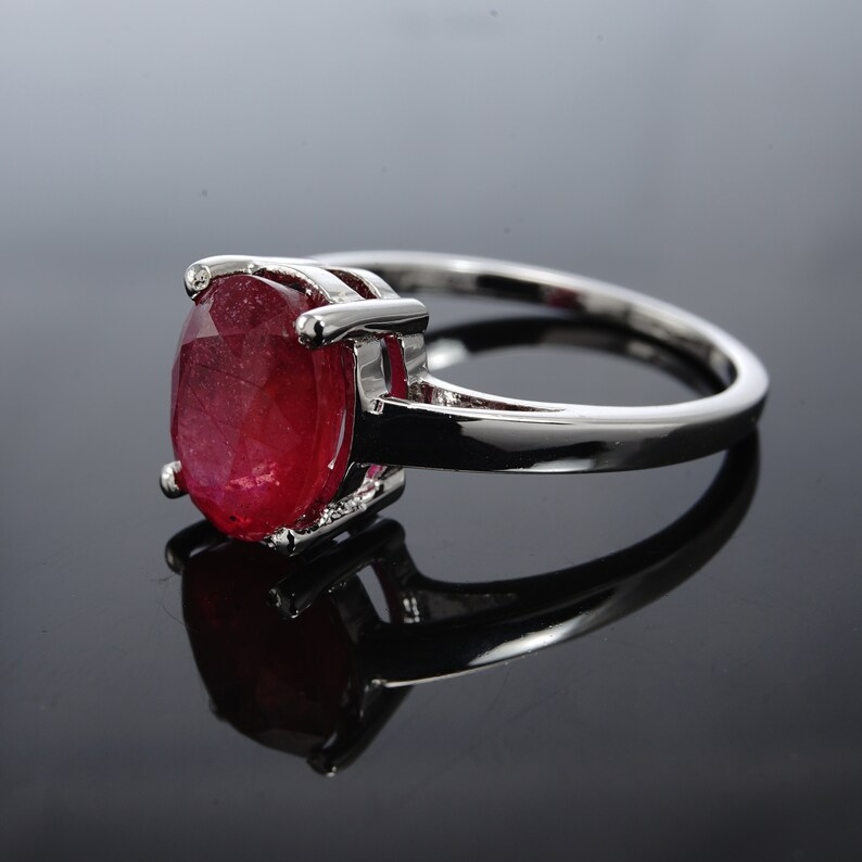Pu&ograve; includere: Un anello d'argento con una grande pietra preziosa di rubino di forma ovale. Il rubino &egrave; di colore rosso intenso e ha una taglio sfaccettato.