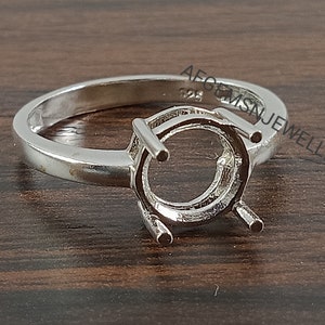 May include: A silver ring setting with a round bezel for a gemstone. The ring is marked "925" on the inside band.