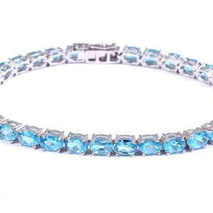 May include: A silver tennis bracelet with oval-shaped blue topaz stones.