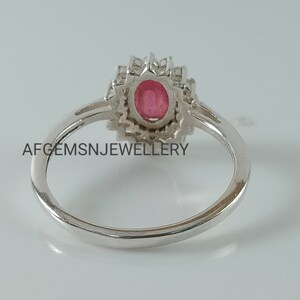 Pu&ograve; includere: Un anello d'argento con una pietra ovale rosa circondata da pietre bianche pi&ugrave; piccole. L'anello &egrave; incastonato in un design floreale.